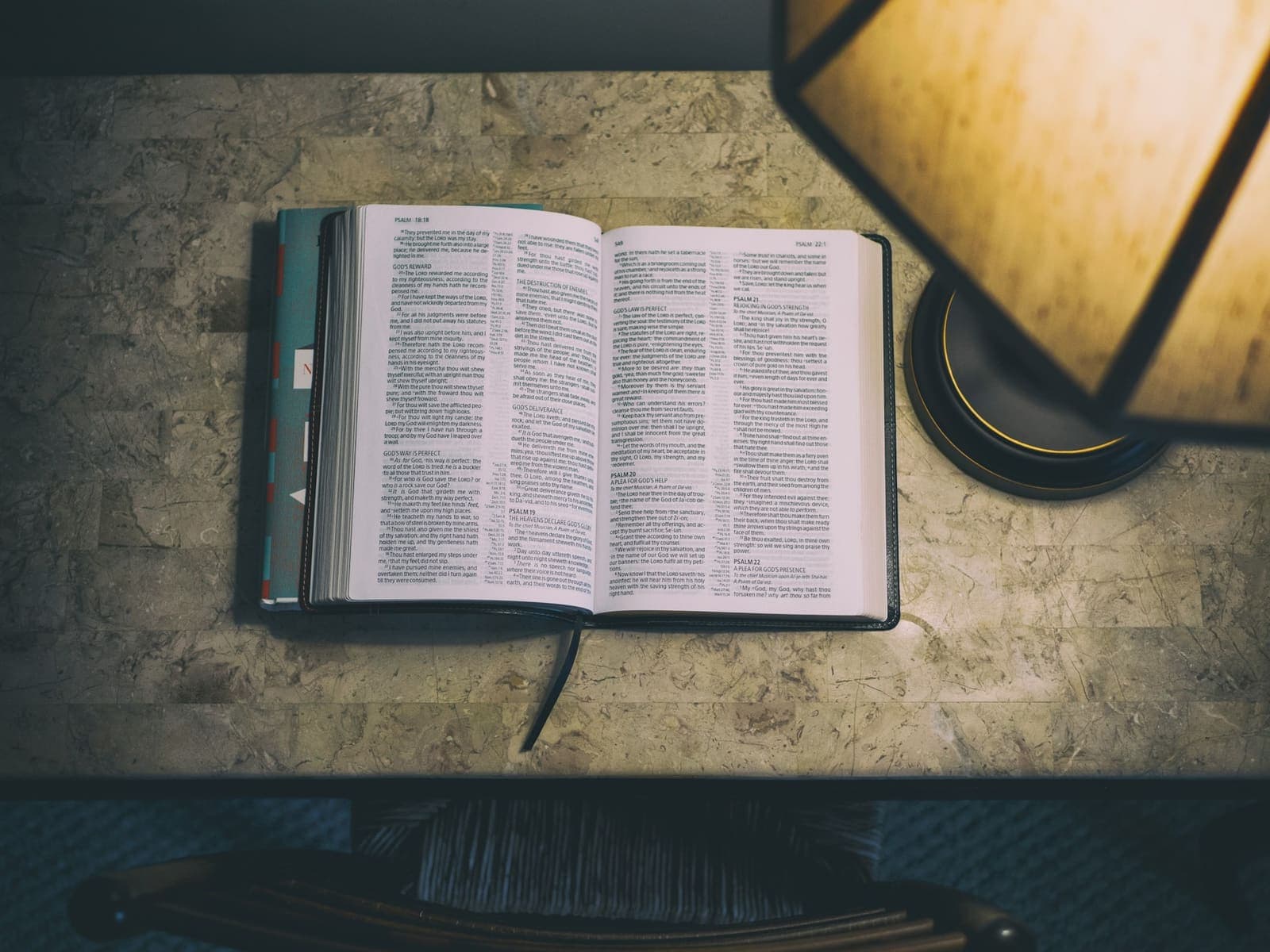 An open Bible on a desk in warm lamplight